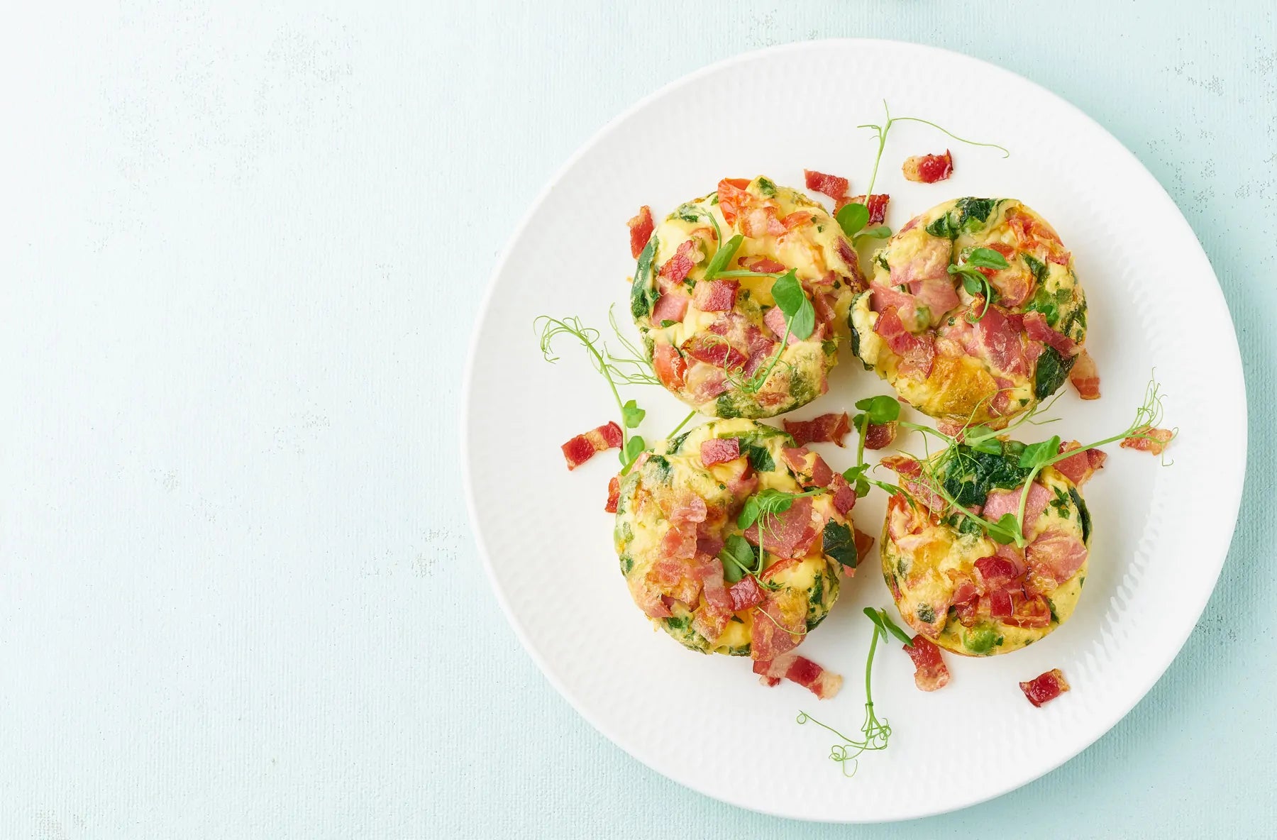 Plate with egg muffins with turkey bacon and herbs